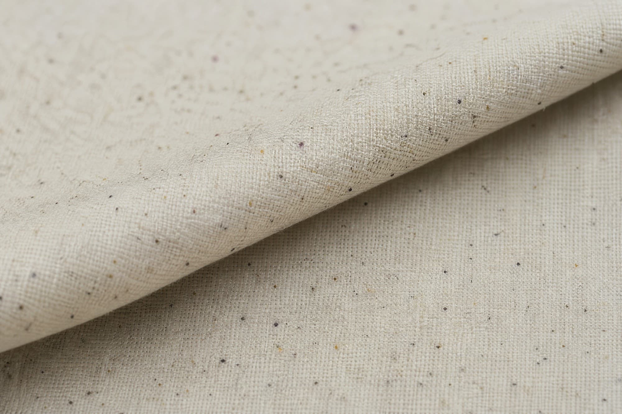 Macro photograph of a folded edge of unbleached calico crossing the frame