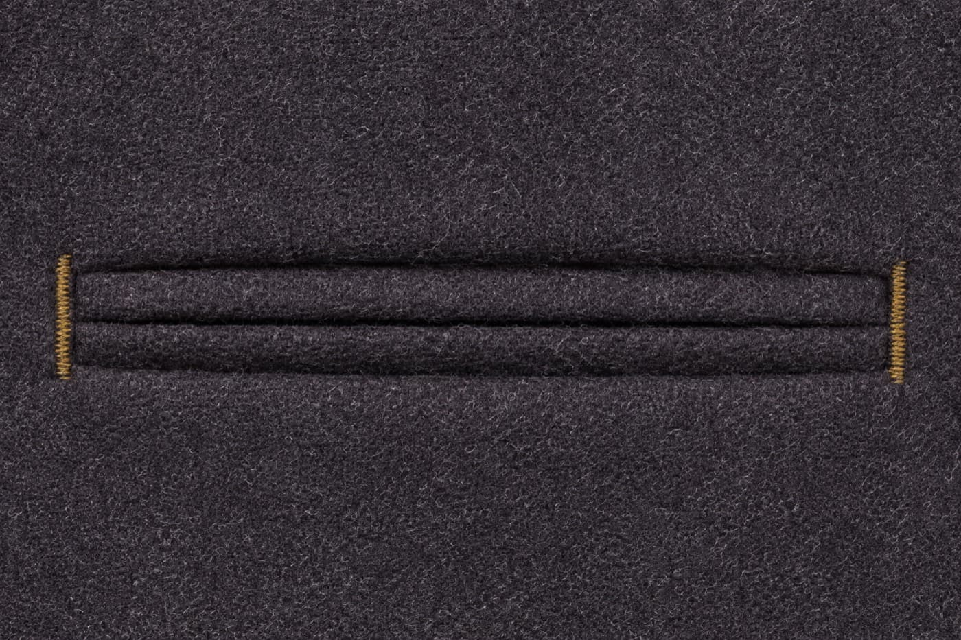 Macro photograph of a finished double-welt pocket opening in charcoal wool