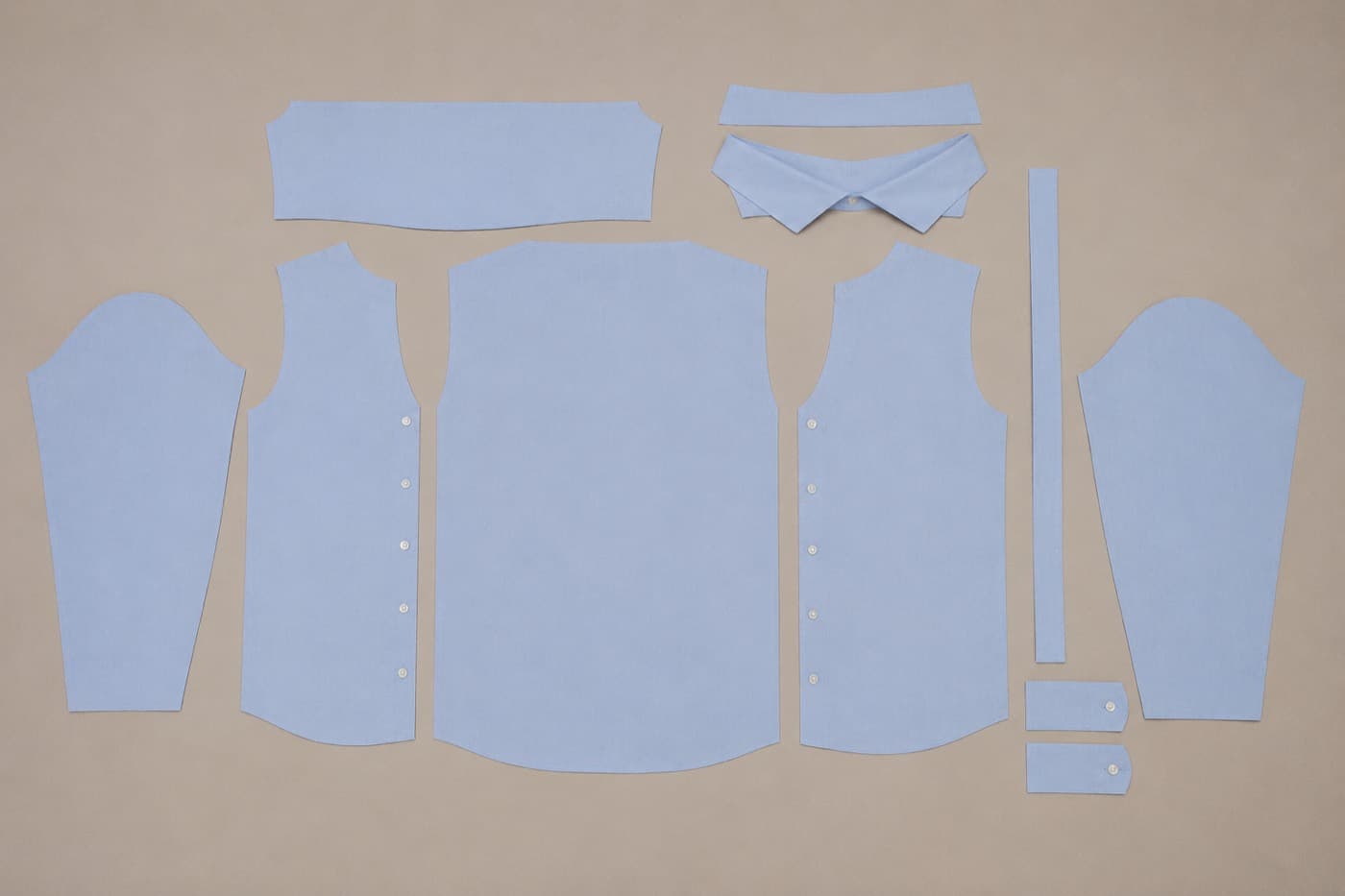 The 13 cut fabric pieces of a button-down shirt, laid out flat